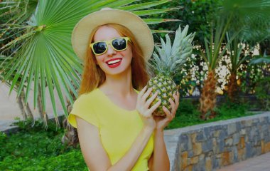 Ananaslı mutlu bir kadının portresi. Palmiye ağacına hasır şapka takıyor.