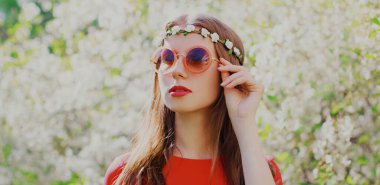 Çiçekli saç bandı takan güzel bir hippi kadının portresi, bahçede güneş gözlüğü.