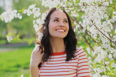 Bir bahar bahçesinde çiçek açan güzel bir kadının portresi. Beyaz bir çiçeğin arka planında.