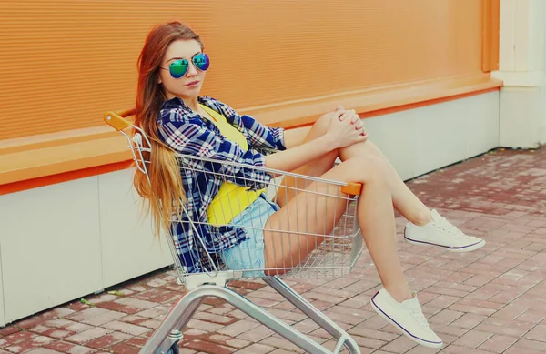 Stilvolle Junge Frau Sitzt Einkaufswagen Auf Orangefarbenem Hintergrund — Stockfoto