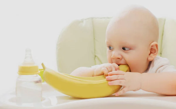 赤ちゃんバナナを食べる家のテーブルに座って — ストック写真