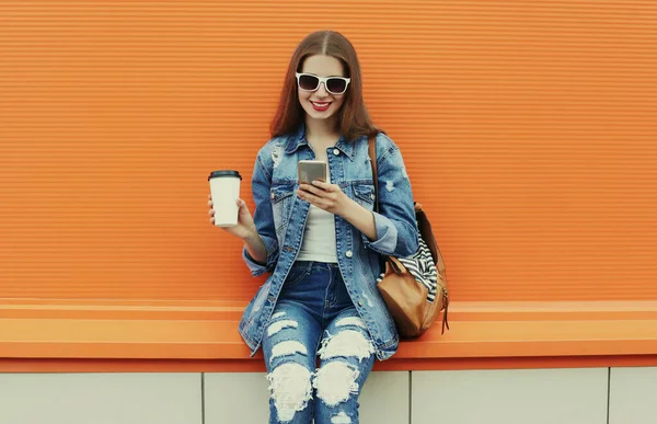 Portret Uśmiechniętej Młodej Kobiety Smartfonem Dżinsowej Kurtce Pomarańczowym Tle — Zdjęcie stockowe