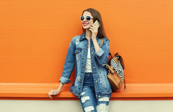 Portret Uśmiechniętej Młodej Kobiety Dzwoniącej Smartfona Dżinsowej Kurtce Pomarańczowym Tle — Zdjęcie stockowe
