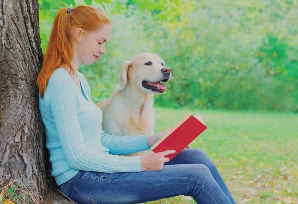 Молодая Женщина Читает Книгу Собакой Ретривером Сидящей Рядом Деревом Парке — стоковое фото