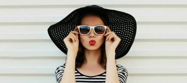Güzel genç bir kadının portresi kırmızı dudaklarını silip siyah yuvarlak bir yaz şapkası takarak tatlı bir hava öpücüğü yolluyor.