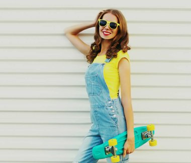 Beyaz arka planda yeşil kaykaylı gülümseyen genç bir kadının portresi.