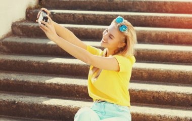 Mutlu gülümseyen genç bir kadın şehirde fotoğraf çekiyor.