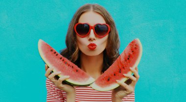 Kırmızı dudaklarını mavi arka planda bir dilim karpuzla silen genç bir kadının portresi.