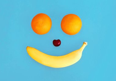 Mavi arka planda iki portakal ve muz meyvesi