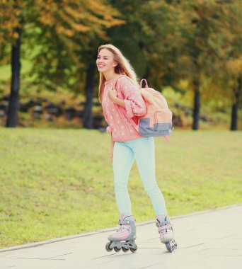 Şehir parkında paten süren mutlu, genç bir kadın.