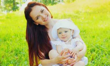 Mutlu anne ve küçük kız bebek portresi Bir yaz parkında çimlerin üzerinde