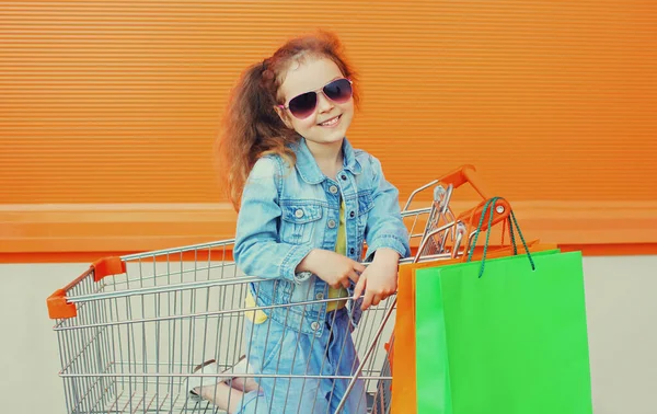 Kislány Gyermek Targoncával Bevásárlószatyrokkal Farmer Ruhát Visel Város Utcáján — Stock Fotó