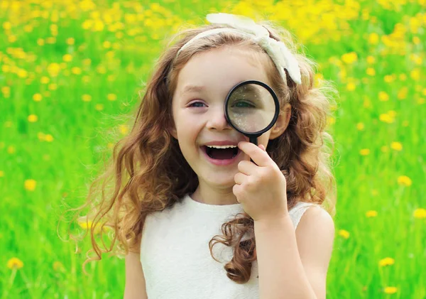 夏の日に草の上の虫眼鏡を通して見ている子供 — ストック写真
