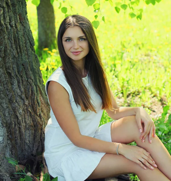 夏の公園で草の上に座っている美しい若い女性の肖像画 — ストック写真