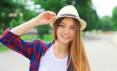 Portrait of young woman wearing a summer straw hat in a city