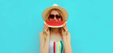 Mavi arka planda şapka takan ve elinde bir dilim karpuzla gülümseyen genç bir kadının yaz portresi.