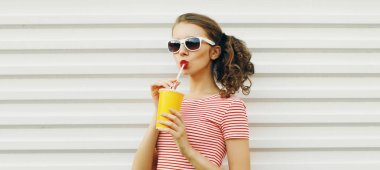 Yaz portresi. Güzel bir genç kadın. Beyaz arka planda taze meyve suyu içiyor.