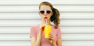 Yaz portresi. Güzel bir genç kadın. Beyaz arka planda taze meyve suyu içiyor.