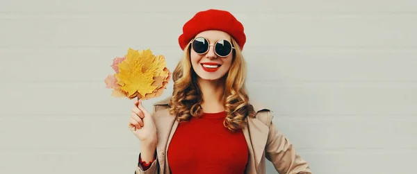 美丽而快乐的年轻女子的秋天肖像 枫叶黄黄 背景灰白 头戴红色法式贝雷帽 — 图库照片