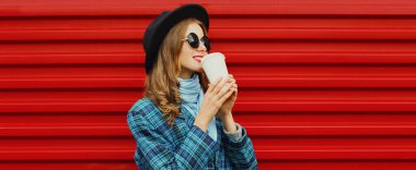 Siyah yuvarlak şapkalı güzel bir kadının portresi, kırmızı arka planda mavi örülmüş bir ceket.