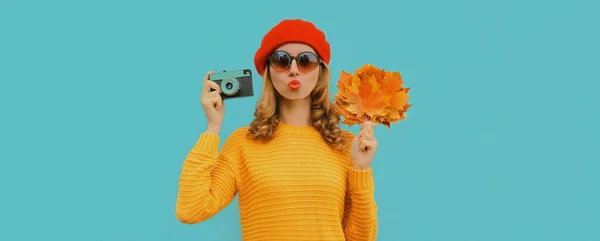 美しいです若いです女性の秋の肖像画フィルムカメラと黄色のカエデの葉はセーターを着て 青の背景にフランス語ベレー帽 — ストック写真