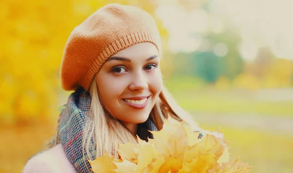 黄色のカエデの葉を持つ美しい笑顔の若い女性の肖像画秋の公園でベレー帽を着て — ストック写真