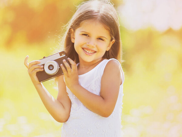 Happy child with retro camera having fun outdoors