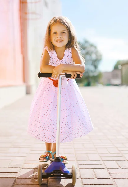 Positive little girl riding a scooter having fun — Stock Photo, Image