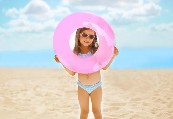 Bambino positivo con cerchio gonfiabile sulla spiaggia divertendosi — Foto Stock