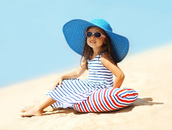 Bonita niña en un vestido a rayas y sombrero relajante en el be — Foto de Stock