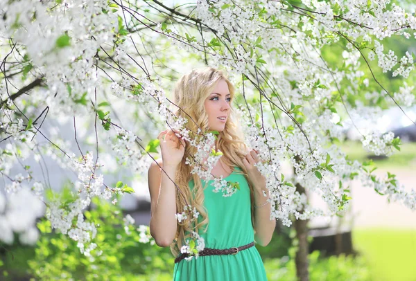 Linda loira bonito em um jardim de primavera olhando para o lado — Fotografia de Stock