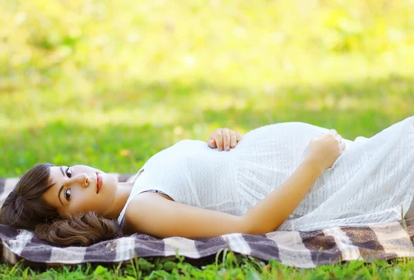 Lovely pregnant woman lying on the grass in summer day — Stock Photo, Image