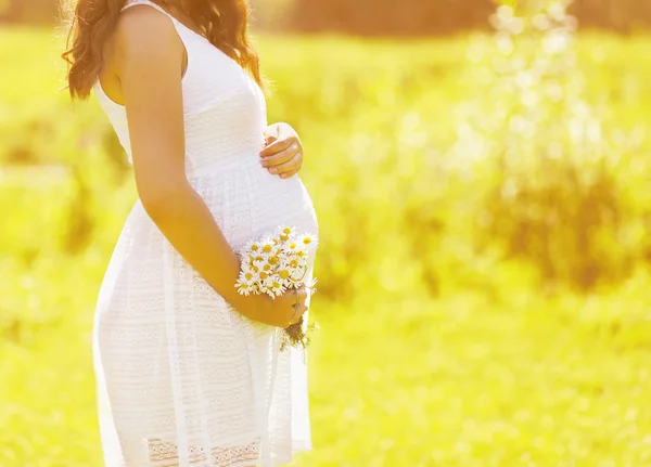 Těhotenství krásná žena s květinami, v létě slunečný den, řízení — Stock fotografie