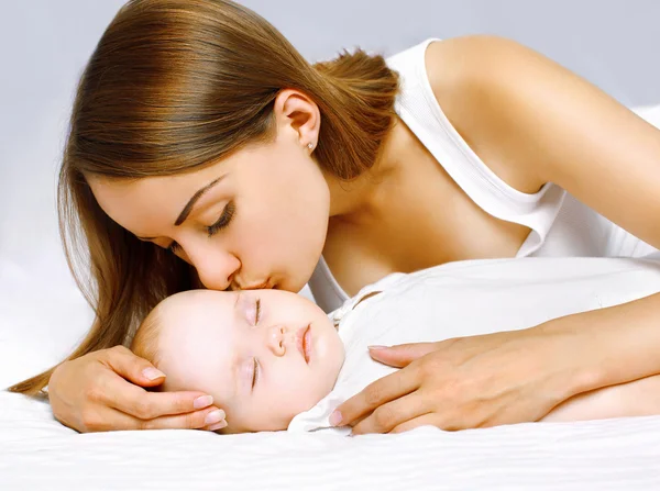 Mãe feliz e bebê dormindo na cama — Fotografia de Stock