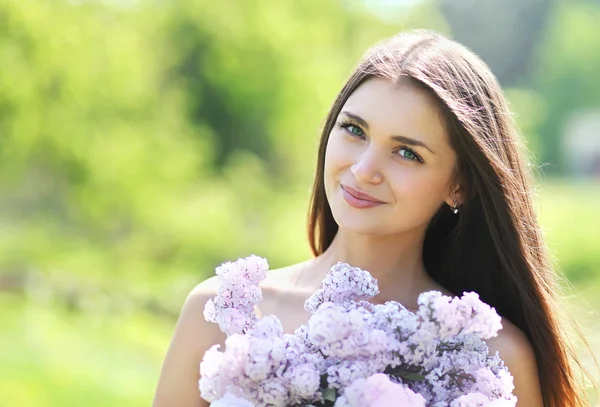 Preciosa linda chica sonriente con un ramo de lilas en verano — Foto de Stock