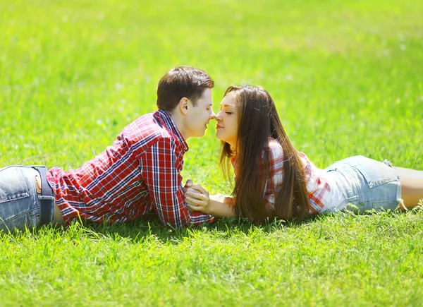 Glad ung par kär i gräset på sommaren solig dag — Stockfoto
