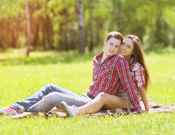 Junges glückliches Paar hat Spaß im Sommer auf dem Gras sitzend, jo — Stockfoto