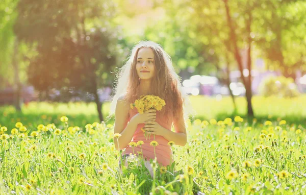 Dandelions ile sarı çayır güneşli fotoğraf genç kız — Stok fotoğraf