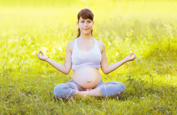 Glad gravid kvinna yoga utomhus på gräset — Stockfoto