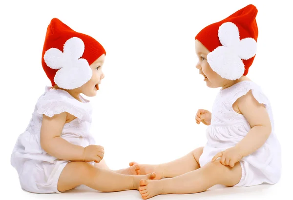 Dos gemelos bebés divertidos en sombreros sentados cara a cara —  Fotos de Stock