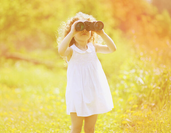 Child looks in binoculars in sunny summer day