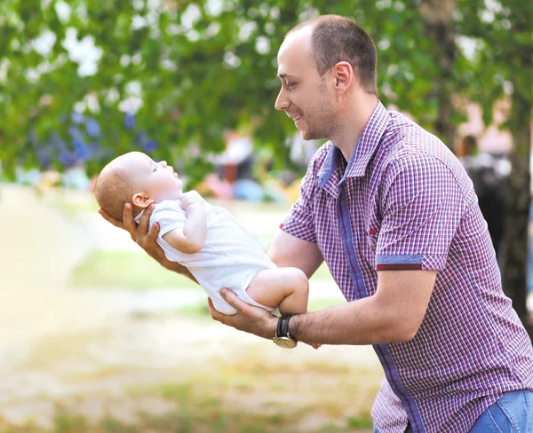 Feliz padre sosteniendo pequeño bebé recién nacido, caminar día de verano —  Fotos de Stock