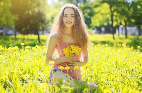 Foto soleada chica feliz en el prado amarillo con dientes de león —  Fotos de Stock