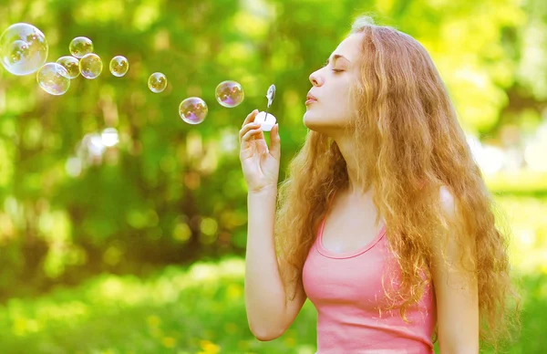 Gadis cantik keriting meniup gelembung sabun bersenang-senang di luar ruangan di su — Stok Foto