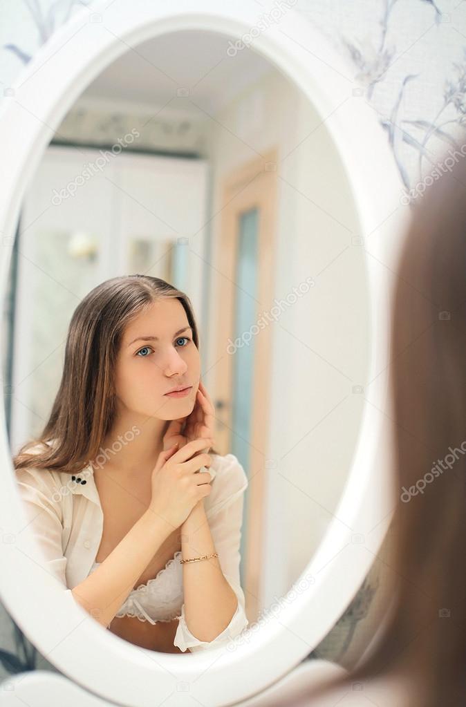 Cute young girl looks at herself in the mirror