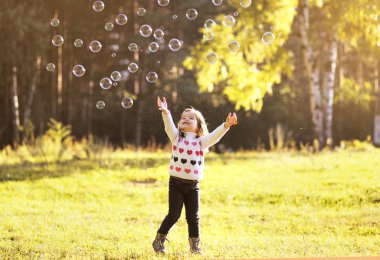 küçük bir çocuk ile baloncuklar sabun içinde güneşli bir sonbahar günü eğlenmek
