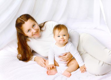 Portre sevimli mutlu anne ve bebek yatakta ev