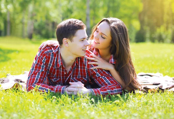 Feliz jovem casal se divertindo no parque na grama sorrindo i — Fotografia de Stock
