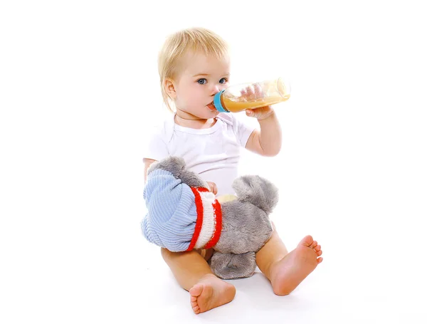 Kleine baby drankjes uit een fles op een witte achtergrond — Stockfoto