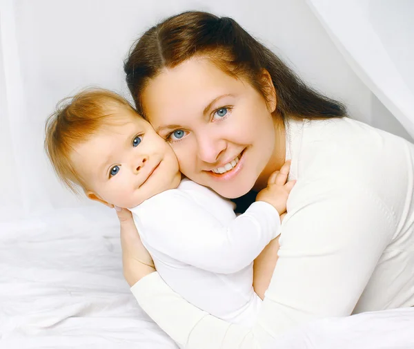 Retrato hermosa madre sonriente y el bebé en la cama —  Fotos de Stock